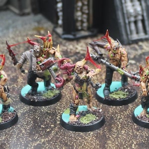 May include: A collection of miniature fantasy figures, each with unique armor and weaponry. The figures are painted in shades of green, brown, and red, and are mounted on circular bases with a blue and green design. The figures are posed in a battle-ready stance.