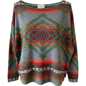 May include: A long-sleeved knit jumper featuring a wide boat neckline and a repeating geometric pattern in shades of grey, green, orange, and deep red. The design includes large diamond shapes and horizontal bands across the front and sleeves.