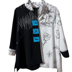 Puede incluir: Chaqueta estampada en blanco y negro con un diseño único. El lado izquierdo es negro con líneas blancas, el lado derecho blanco con contornos florales negros. Cuenta con tres botones cuadrados azules y cuello alto.