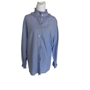 Op de afbeelding: Een lichtblauw overhemd met een gerimpelde kraag en manchetten. Het shirt met lange mouwen heeft een verticaal gestreept patroon en is aan de voorkant dichtgeknoopt met witte knopen. Het shirt wordt gepresenteerd op een witte mannequin.
