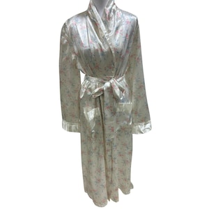 May include: A cream-colored satin robe with a floral pattern of pink and blue flowers. The robe has a shawl collar, a matching belt, and pockets. The cuffs and edges are trimmed with a satin border.