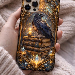 May include: A phone case featuring a detailed illustration of a black raven perched atop a stack of books, with a lit candle. The design includes a starry night sky and ornate gold framing, creating a mystical aesthetic.