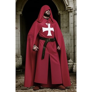 Op de afbeelding: Een bordeauxrode cape en gewaad set met een wit kruis embleem. Het kostuum bevat een zwarte leren riem. De outfit is ontworpen voor historische re-enactment of thema-evenementen.