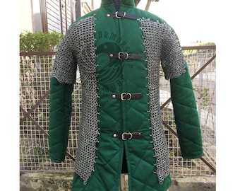 May include: A green quilted medieval gambeson with chainmail sleeves and accents. The front features three leather straps with buckles. The garment is displayed on a mannequin.