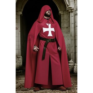 Op de afbeelding: Een bordeauxrode cape en gewaad set met een wit kruis embleem. Het kostuum bevat een zwarte leren riem. De outfit is ontworpen voor historische re-enactments of thema-evenementen.