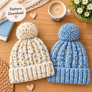 May include: Two knit beanies with pom-poms, one in cream and one in blue, both featuring a speckled multi-colored yarn pattern. Each hat has a ribbed cuff and a large, textured pom-pom on top. The image includes text that reads Pattern Download.