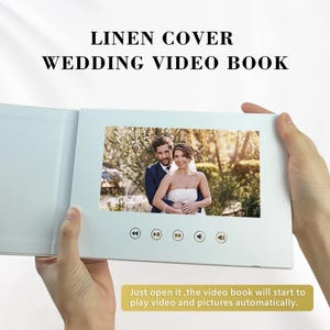 May include: A white linen cover wedding video book displaying a photo of a couple. The book features playback controls and the text "LINEN COVER WEDDING VIDEO BOOK". The text at the bottom reads, "Just open it, the video book will start to play video and pictures automatically."
