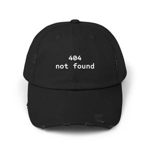 May include: Black distressed baseball cap with the text "404 not found" in white. The cap has a curved brim and a distressed, worn look, with visible tears and fraying around the edges.