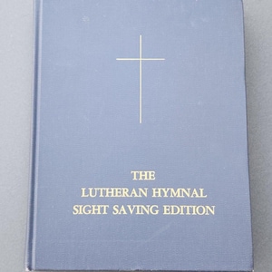 May include: A blue hardback book with a gold cross and the title "THE LUTHERAN HYMNAL SIGHT SAVING EDITION" printed on the front cover.