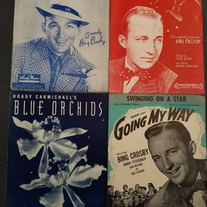 May include: Four vintage sheet music covers featuring Bing Crosby. Titles include "Now Is The Hour," "Between A Kiss And A Sigh," "Blue Orchids," and "Going My Way." The covers showcase portraits and illustrations in various colors, including blue, red, and white.