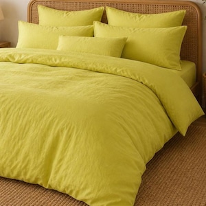 May include: A bed set featuring a duvet cover and several pillowcases in a vibrant yellow-green color. The bedding is arranged on a bed with a woven headboard. The set includes a fitted sheet, duvet cover, and multiple pillowcases, creating a coordinated look.