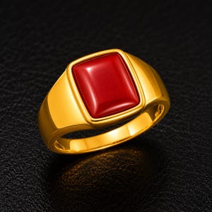 Puede incluir: Un anillo de sello de oro con una piedra roja oscura, lisa y rectangular engastada en el centro. La banda es de oro pulido con una construcción sólida y gruesa, que muestra una superficie limpia y reflectante y una incrustación roja vibrante.