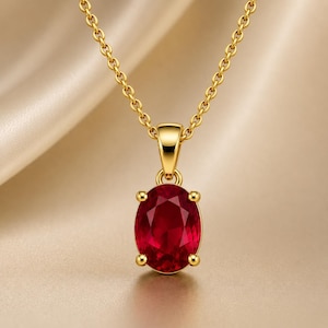 Può includere: Una collana in oro con un ciondolo in pietra preziosa rosso intenso dal taglio ovale, fissato da una montatura a quattro griffe. Il ciondolo è sospeso a una delicata catenina d'oro con piccoli anelli circolari uniformi.