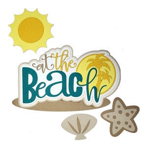 May include: A set of paper cutouts for scrapbooking or card making. The cutouts include a sun, a seashell, a starfish, and a palm tree with the text "at the beach" in teal.