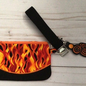 May include: A small black zippered pouch with a flame pattern and a black strap with a motorcycle charm.