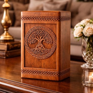 May include: A wooden urn with a carved Tree of Life design. The rectangular urn is brown with intricate Celtic knotwork borders. The tree is centered on the front panel, with detailed roots and branches.