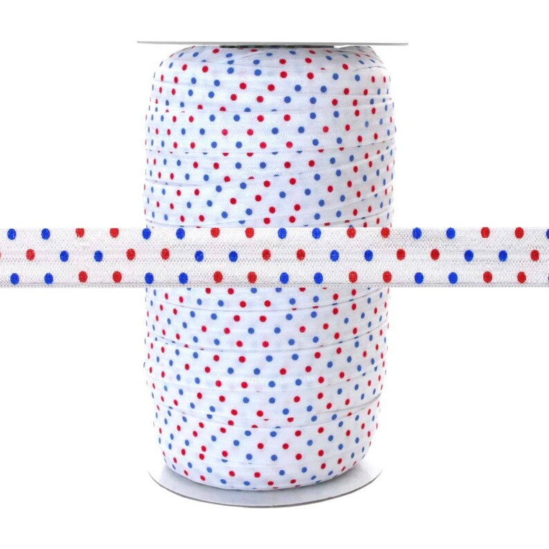 May include: A spool of white elastic with red and blue polka dots. The elastic is wound around a white cardboard spool.