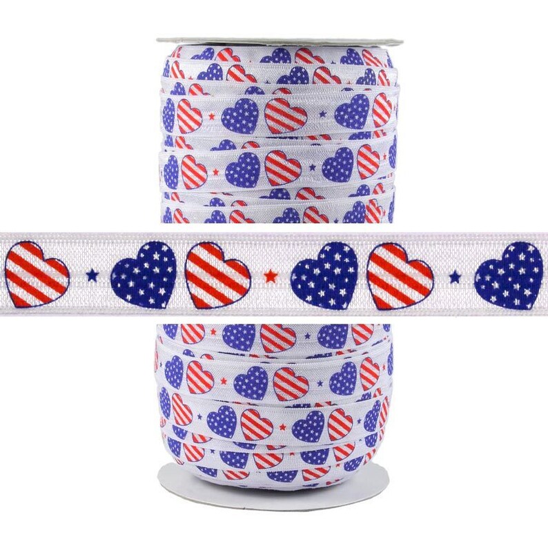 May include: A roll of white elastic with red, white, and blue heart-shaped designs. The hearts are patterned with stars and stripes, resembling the American flag.