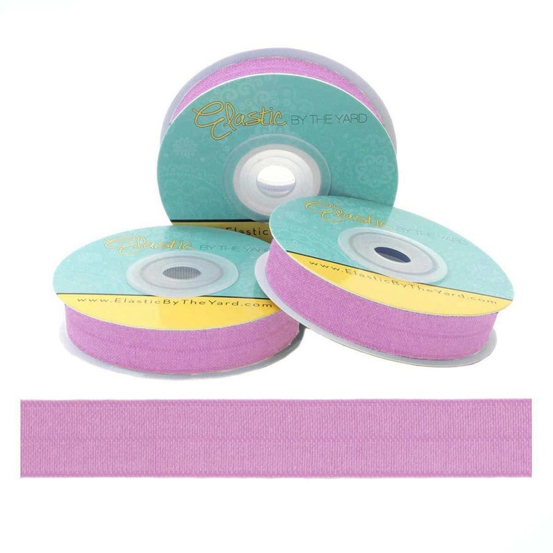 May include: Three spools of light pink elastic ribbon with the text "Elastic By The Yard" and the website address "www.ElasticByTheYard.com" printed on the spools.