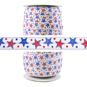 May include: A spool of white elastic with a red, blue, and white star pattern. The elastic is wound around a cardboard spool.