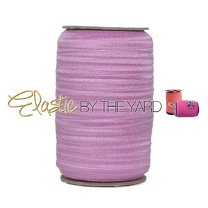 May include: A spool of light purple elastic, wound tightly, with the text "Elastic By The Yard" printed on the side.