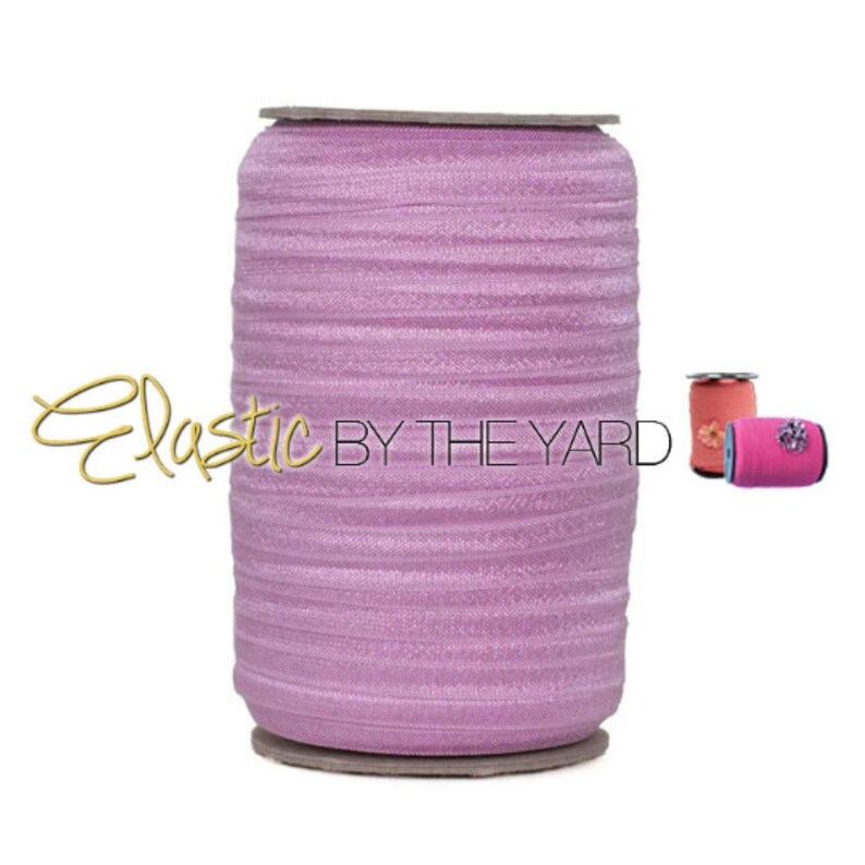 May include: A spool of light purple elastic, wound tightly, with the text "Elastic By The Yard" printed on the side.
