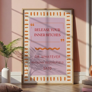 Könnte beinhalten: Ein gerahmter Kunstdruck mit dem Text "Release Your Inner Bitches" in einem rosa Rechteck, mit orangefarbenen Akzenten und einem Holzrahmen. Der Druck enthält auch die Worte "Or Whatever Natasha Bedingfield Said".