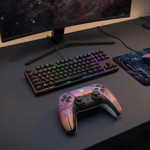 May include: A wireless video game controller featuring a sunset-themed graphic with palm tree silhouettes and a central text logo, positioned in front of a black mechanical keyboard with RGB lighting and a curved computer monitor display.