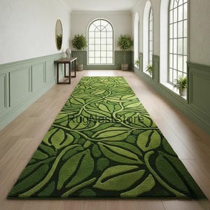 May include: A long, rectangular green rug with a leaf pattern, displayed in a hallway with light wood flooring. The rug features varying shades of green, creating a textured, three-dimensional effect. The text "RugNestStore" is visible on the rug.