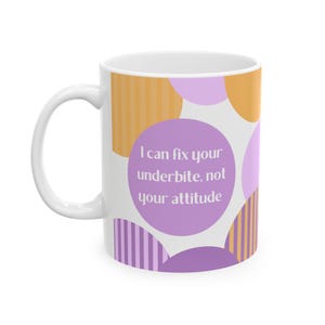 Puede incluir: Taza de cerámica blanca con asa, con un diseño de formas naranjas y moradas. La taza tiene el texto "I can fix your underbite, not your attitude" en un círculo morado. Un regalo divertido y peculiar.