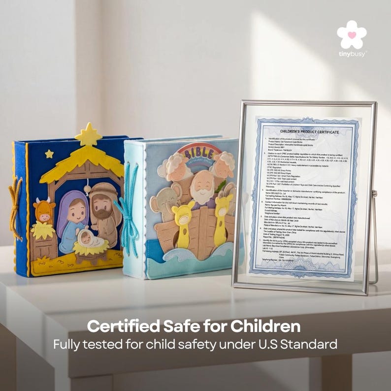 Pu&ograve; includere: Due libri di storie in feltro con illustrazioni colorate, uno raffigurante una scena della nativit&agrave; e l'altro l'Arca di No&egrave;. &Egrave; visibile un certificato incorniciato. Il testo recita "Certificato sicuro per bambini".