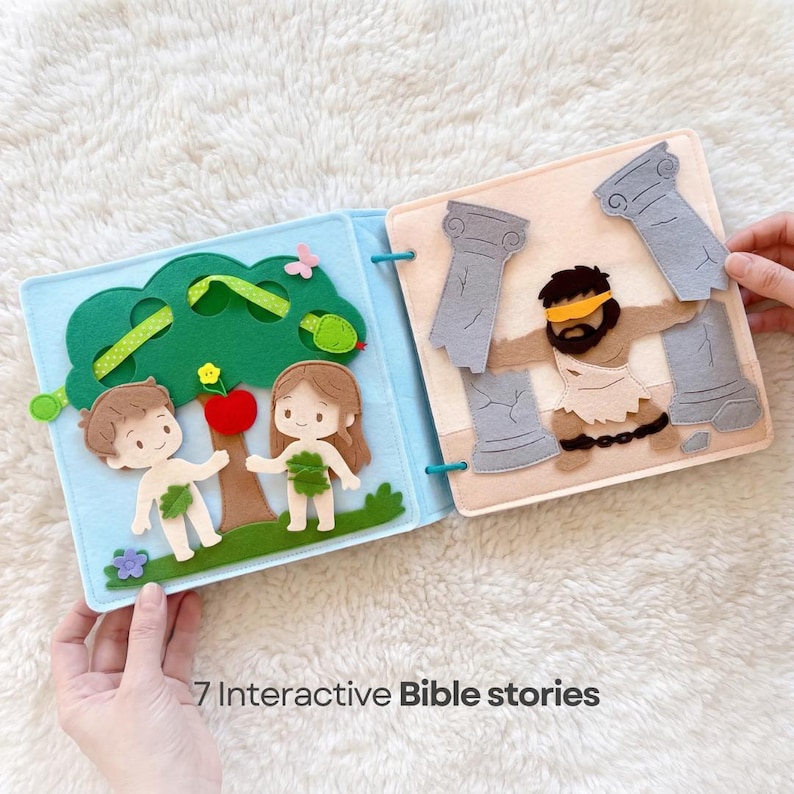 Pu&ograve; includere: Un libro in feltro aperto su due pagine. Una pagina mostra Adamo ed Eva vicino a un albero con una mela rossa. L'altra pagina raffigura un uomo con una benda e delle colonne. Il testo "7 Interactive Bible stories" &egrave; in basso.