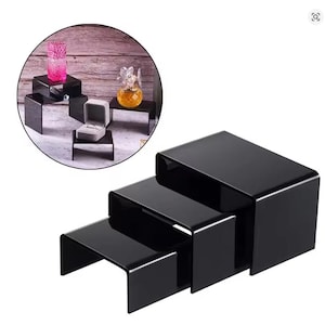 Peut inclure: Ensemble de trois présentoirs noirs en acrylique. Les présentoirs rectangulaires ont des coins arrondis et une finition brillante. Ils sont conçus pour s'emboîter pour le stockage et sont parfaits pour présenter des bijoux, des objets de collection ou de petits articles.