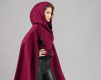 May include: A woman wearing a long, burgundy hooded cape with black leather leggings and black thigh-high boots.