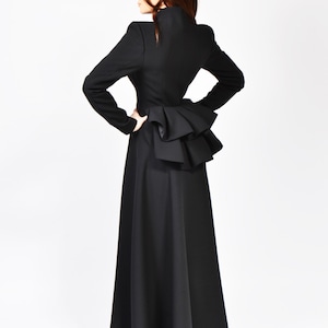 May include: A black long-sleeved dress with a ruffled detail at the back.