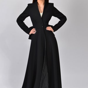 May include: A long black coat with a fitted waist and a flowing skirt. The coat has a V-neckline and a single button closure at the waist.