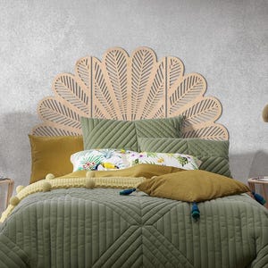 May include: A bedroom with a wooden, fan-shaped headboard. The bed is made with a green quilted duvet and pillows in olive and mustard tones. A decorative throw with pom-poms adds texture. The bed also has a floral patterned pillow.