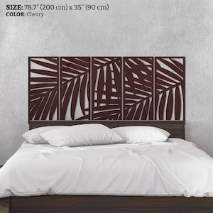 May include: Cherry-colored, laser-cut headboard with a palm leaf design. The headboard is 78.7 inches (200 cm) wide and 35 inches (90 cm) high, mounted above a bed with white bedding.
