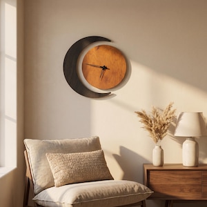 May include: A wall clock featuring a circular wooden face with a warm brown grain and black hands, partially framed by a dark, crescent-shaped wooden element. The clock is mounted on a plain wall above a chair and a wooden side table with a lamp.