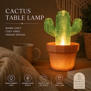 以下が含まれることがあります： 温かい光を放つサボテン型のテーブルランプ。緑色のサボテンはテラコッタ色の鉢に入っています。画像には「CACTUS TABLE LAMP」と「WARM LIGHT. COZY VIBES. UNIQUE DESIGN.」と書かれています。