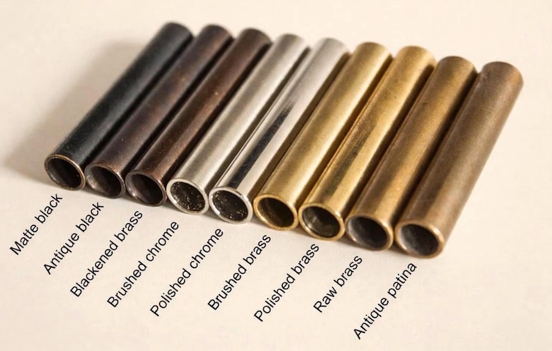 May include: An assortment of metal tubes in various finishes, including matte black, antique black, and polished brass. The image displays a range of colors and textures, with labels identifying each finish. The tubes are cylindrical and appear to be components or decorative elements.