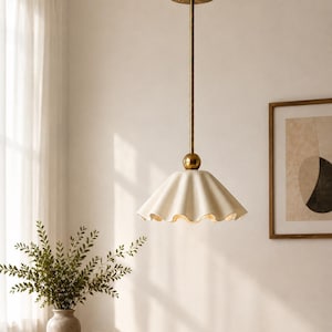 May include: A pendant light fitting featuring a scalloped, off-white ceramic shade suspended by a slender, brushed brass-toned metal rod. The fitting includes a matching brass-toned circular ceiling canopy and a small spherical accent piece.