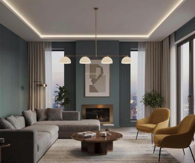 May include: A linear chandelier featuring four white semi-spherical glass shades suspended from a thin gold-toned metal rod. The fixture is centered horizontally, providing downward illumination over a circular wooden coffee table in a living room.