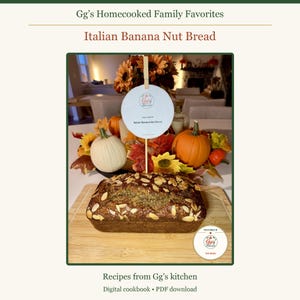 May include: A loaf of banana nut bread topped with sliced almonds on a wooden cutting board. A circular sign on a stick reads Gg's Homecooked Family Favorites and Italian Banana Nut Bread, surrounded by decorative pumpkins and autumn leaves.
