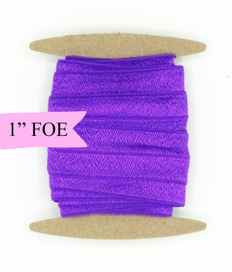 May include: A spool of 1" purple fold over elastic (FOE) on a wooden dowel.