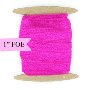 May include: A spool of 1" wide pink fold over elastic (FOE) on a wooden dowel.