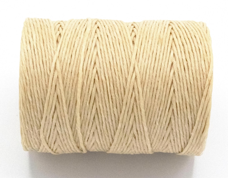 Puede incluir: Un carrete de hilo de color natural. El hilo est&aacute; enrollado firmemente, creando una forma cil&iacute;ndrica. El color es beige claro y la textura parece ligeramente &aacute;spera. Este hilo es adecuado para manualidades, envolver regalos y varios proyectos de bricolaje.