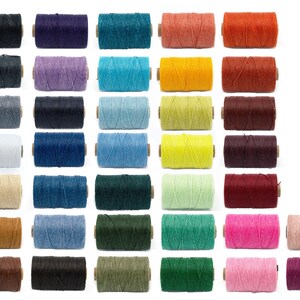 May include: A collection of 24 spools of 4-ply twine in various colors, including black, purple, teal, orange, gray, lavender, turquoise, yellow, brown, navy, blue, light blue, lime green, dark red, beige, denim, forest green, sea green, pink, and light pink.
