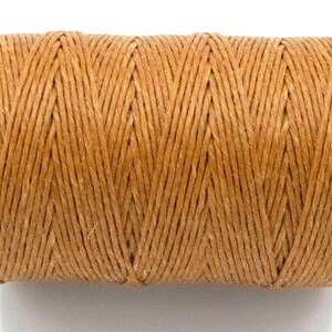 Puede incluir: Un carrete de hilo de color natural. El hilo est&aacute; enrollado firmemente, creando una forma cil&iacute;ndrica. El color es un tono c&aacute;lido y terroso, y la textura parece ligeramente &aacute;spera. Este suministro artesanal es adecuado para varios proyectos.