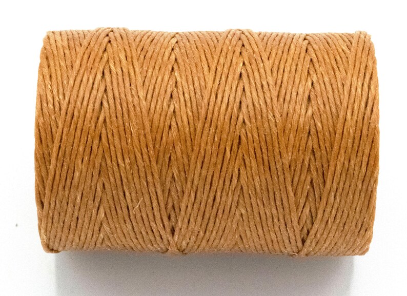 Puede incluir: Un carrete de hilo de color natural. El hilo est&aacute; enrollado firmemente, creando una forma cil&iacute;ndrica. El color es un tono c&aacute;lido y terroso, y la textura parece ligeramente &aacute;spera. Este suministro artesanal es adecuado para varios proyectos.